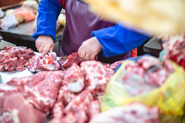 the shop assistant presents a piece of meat and cuts half of it for the buyer. selective focus photo from the natural home market with meat horned animals
