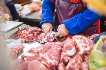 the shop assistant presents a piece of meat and cuts half of it for the buyer. selective focus photo from the natural home market with meat horned animals