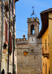 View of the old clocktower, erected in the 17th century, from a narrow lane in Pietralunga historic center, a small town in the Umbrian countryside