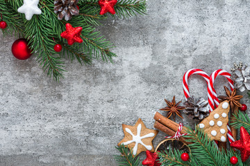 Christmas composition made of fir branches, decorations, berries, candy, gingerbread and pine cones on concrete table
