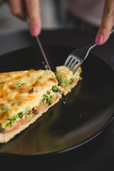 the process of eating girls in a cafe. Close up Photo of female hands holding fork and knife cutting a piece of salty pie