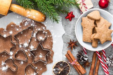 Christmas gingerbread cookies with fir tree branches, gift boxes and decorations on gray concrete background. top view