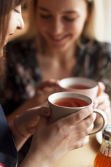 05.08.2019 Kyiv, Ukraine: two pretty women holding mugs of delicious hot tea, drinking and having fun talking