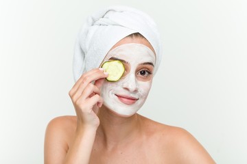 Young caucasian woman enjoying of a facial mask treatment with cucumber