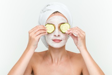 Young caucasian woman enjoying of a facial mask treatment with cucumber