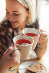 05.08.2019 Kyiv, Ukraine: two pretty women holding mugs of delicious hot tea, drinking and having fun talking