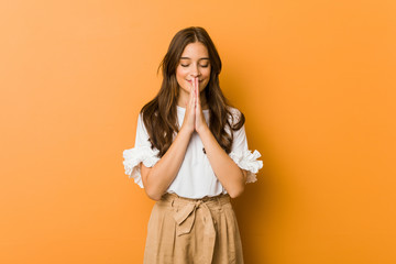 Young caucasian woman holding hands in pray near mouth, feels confident. - obrazy, fototapety, plakaty