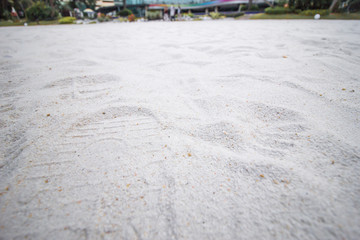 Closeup of sand pattern of a beach with some footprints as background. Got some kids' footprints