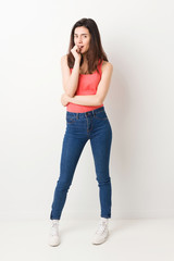 Full body young woman on white background relaxed thinking about something looking at a copy space.