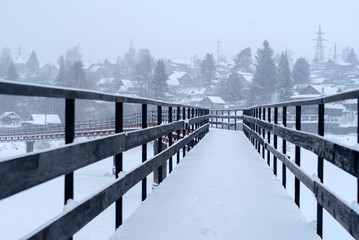 Naklejka premium snow-covered bridge over the river in the winter countryside