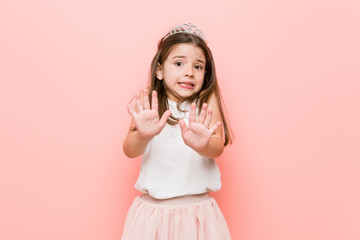 Little girl wearing a princess look rejecting someone showing a gesture of disgust.