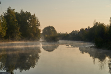 Fototapeta na wymiar A quiet dawn over the lake in a Sunny hazy light. Autumn time.