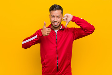 Young filipino fitness man showing thumbs up and thumbs down, difficult choose concept