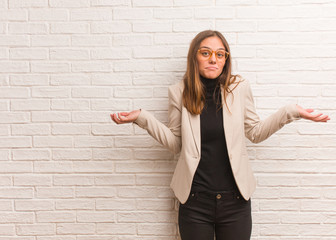 Young pretty business entrepreneur woman doubting and shrugging shoulders