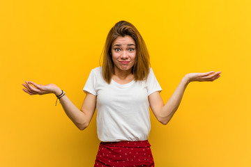 Young natural caucasian woman doubting and shrugging her shoulders in questioning gesture.