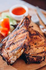 two appetizing pieces of fried ribs served on a wooden board with greens, and grilled vegetables