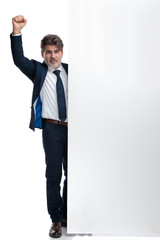 Happy businessman celebrating besides a blank billboard
