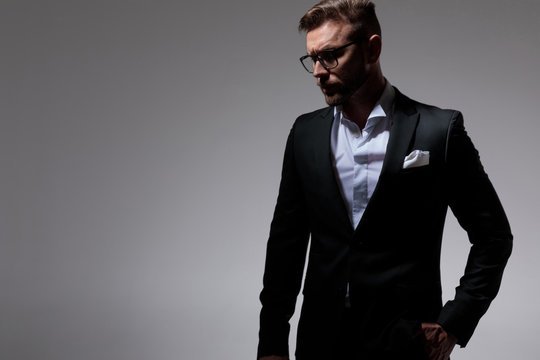  man in tuxedo wearing glasses holding one hand in pocket