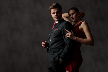 man with hand in pocket and woman holding his arm