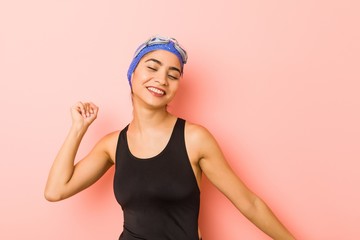 Young arab swimmer woman isolated dancing and having fun.