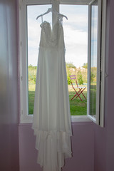 wedding dress hanging on a hanger at the window