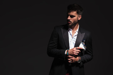 elegant man fixing his cufflinks and looks away