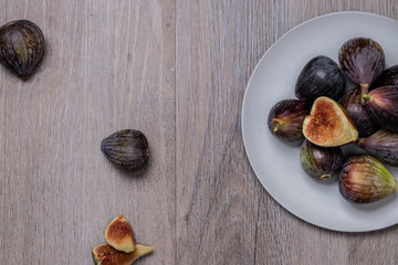 Higos ecológicos sobre plato gris y fondo de madera