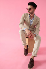 attractive young man sitting on wooden box