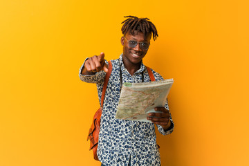 Young rasta black man holding a map cheerful smiles pointing to front.