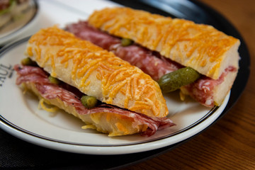 delicious baguette sandwich with ham and salami served on a plate in a bekery shop in London.