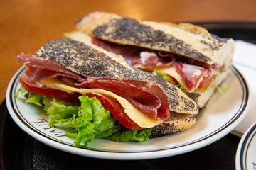 delicious baguette sandwich with ham and salami served on a plate in a bekery shop in London.