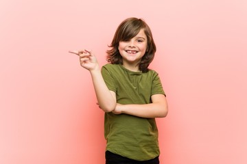 Little boy smiling cheerfully pointing with forefinger away.