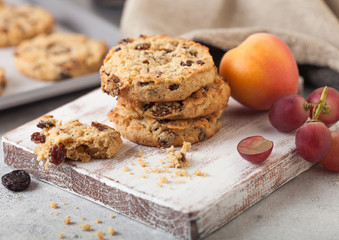 Homemade organic oatmeal cookies with raisins and apricots with baking tray on light background. Grapes and apricot