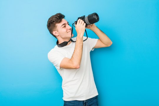 Teenager caucasian man taking photos with a reflex camera