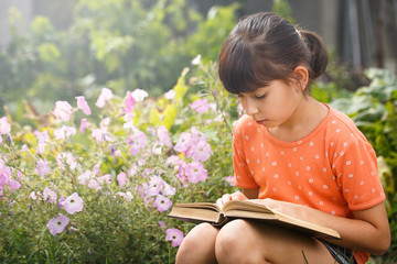 Cute girl is reading outdoors on an sunny day, international literacy day.