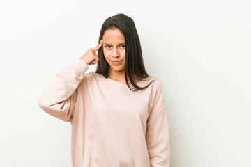 Young cute hispanic teenager woman pointing temple with finger, thinking, focused on a task.