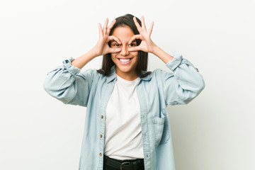 Fototapeta premium Young hispanic woman showing okay sign over eyes