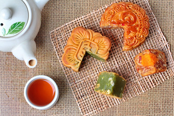 Round mooncake.8 grains and salted eggs and squred mooncake filled red beans, stirred in green tea and chopped macadamia nuts served  with tea and teapot.