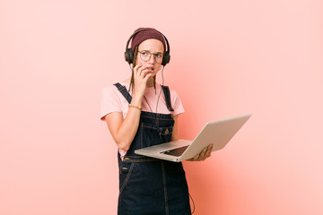 Young caucasian woman holding a laptop biting fingernails, nervous and very anxious.
