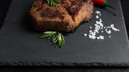 fried steak on black plate with spices on black table