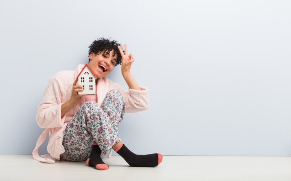 Young african american woman sitting holding a house icon