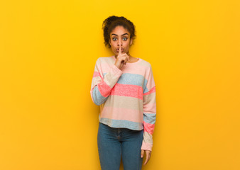 Young black african american girl with blue eyes keeping a secret or asking for silence