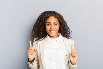 Young african american business woman indicates with both fore fingers up showing a blank space.
