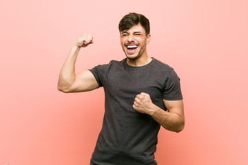 Young hispanic casual man raising fist after a victory, winner concept.