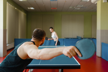 Man and woman playing ping pong, focus on racket