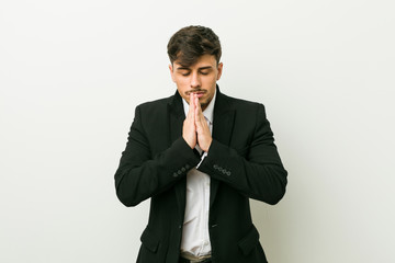 Young business hispanic man holding hands in pray near mouth, feels confident.