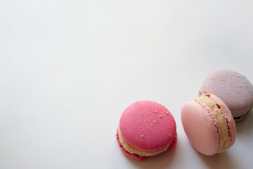Three sweet macaron cakes or French macaroons isolated on white background close up with a copy space
