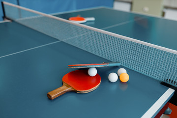 Ping pong rackets and balls on game table with net