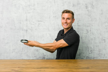 Young handsome man holding a magnifying glass holding a copy space on a palm.