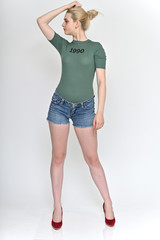 Full length vertical Portrait of a cute blonde student girl, a young woman in a green T-shirt and blue shorts with beautiful curly hair on a white background in various poses.